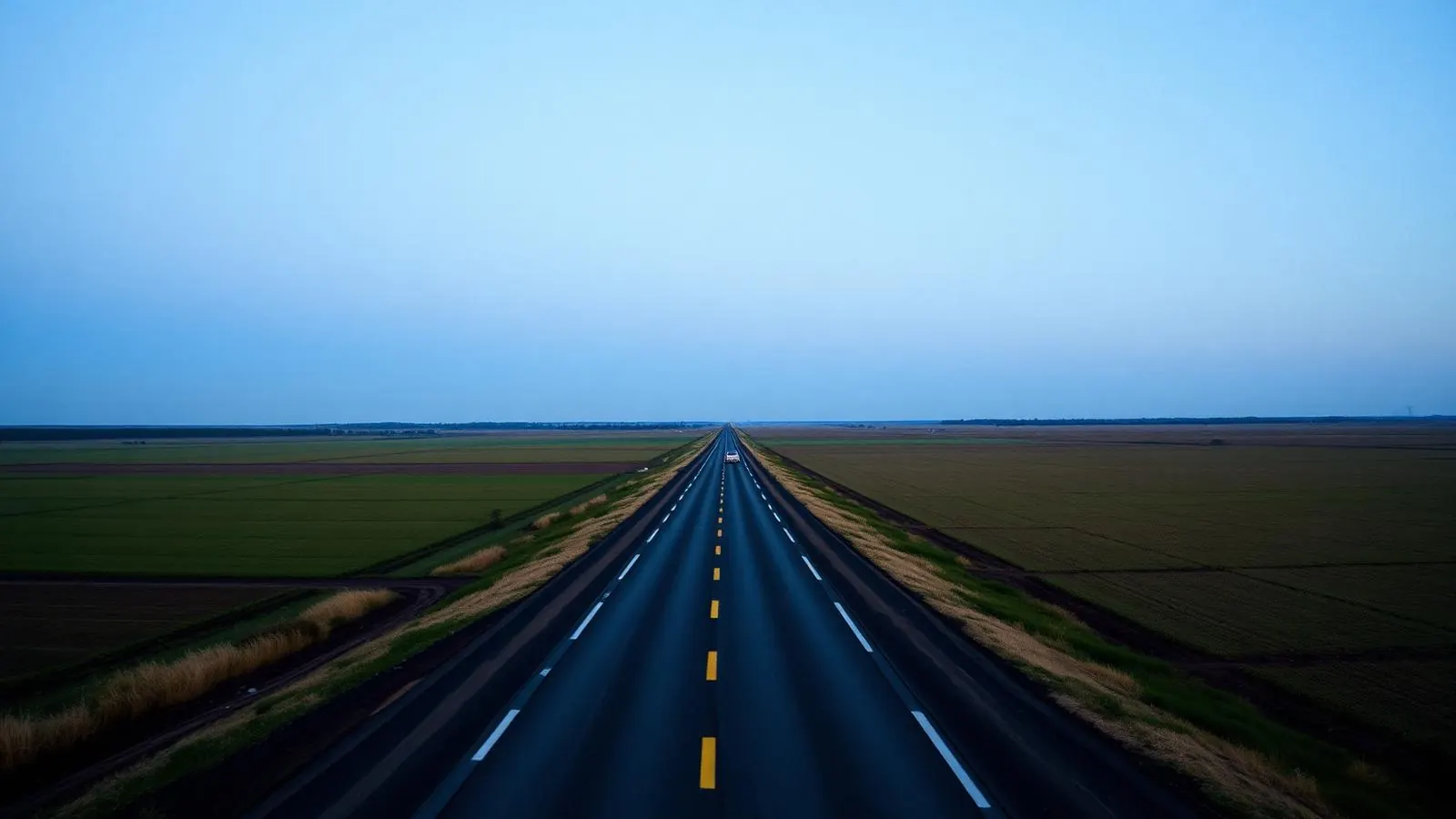 Rodovia asfaltada atravessando lavoura plana até o horizonte